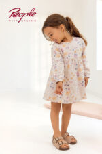 Mädchen trägt ein Langarmkleid mit Blumenmuster in Puderrosa von People Wear Organic