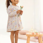 Mädchen trägt ein Kleid mit Blumenmuster in Puderrosa von People Wear Organic