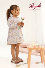 Mädchen trägt ein Kleid mit Blumenmuster in Puderrosa von People Wear Organic